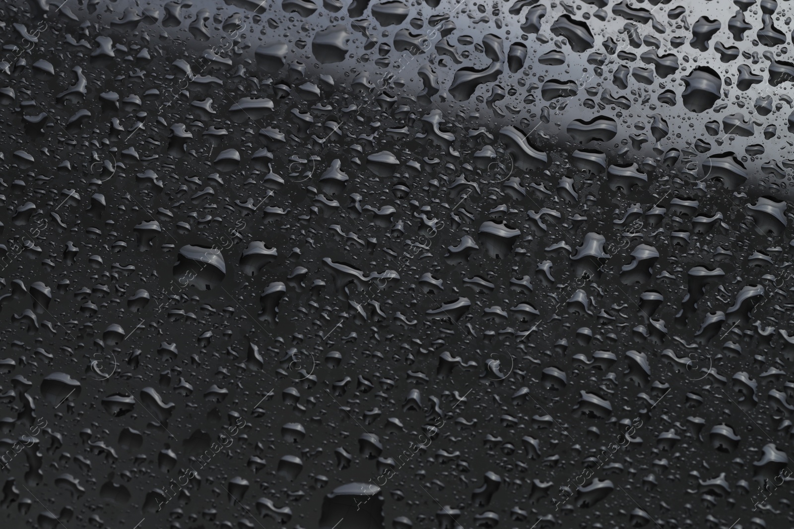 Photo of Water drops on dark grey glass surface, top view