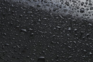 Photo of Water drops on dark grey glass surface, top view