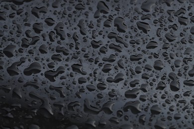 Water drops on dark grey glass surface, closeup