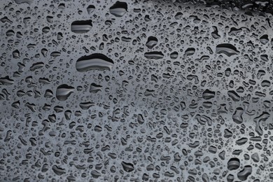 Water drops on dark grey glass surface, closeup