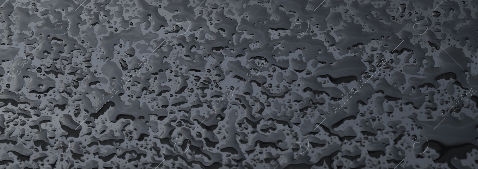 Photo of Water drops on grey glass surface, closeup