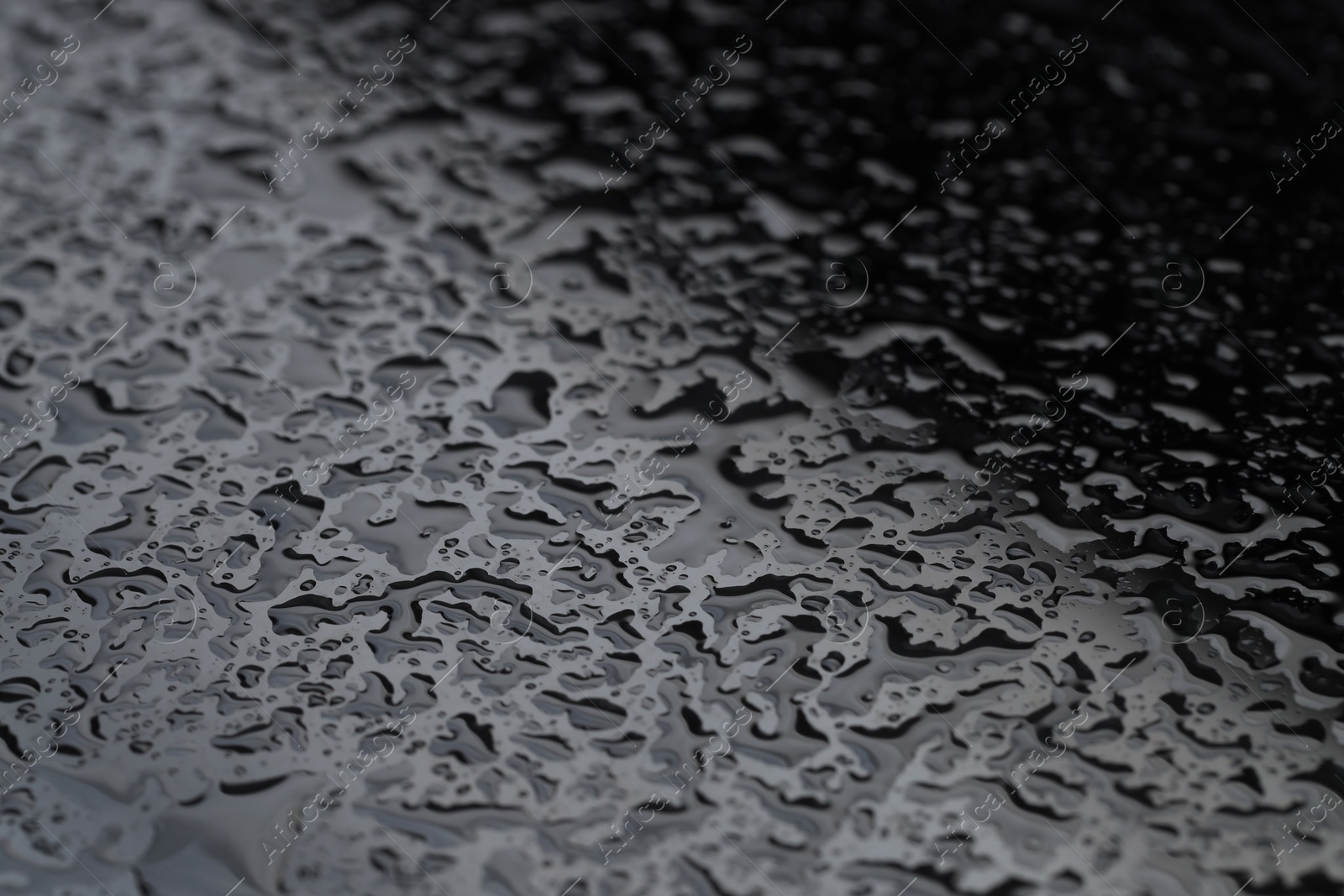 Photo of Water drops on grey glass surface, closeup