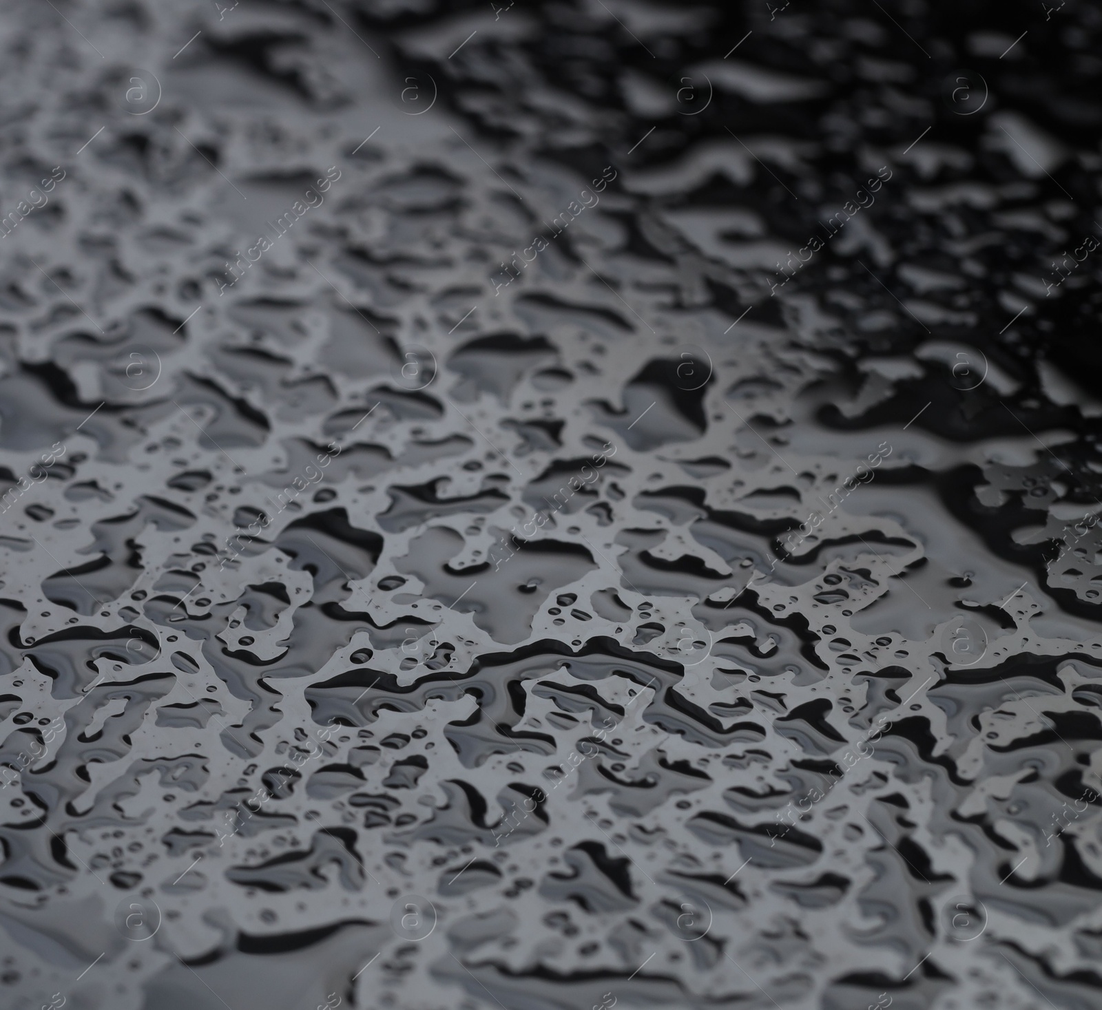 Photo of Water drops on grey glass surface, closeup