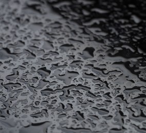 Water drops on grey glass surface, closeup