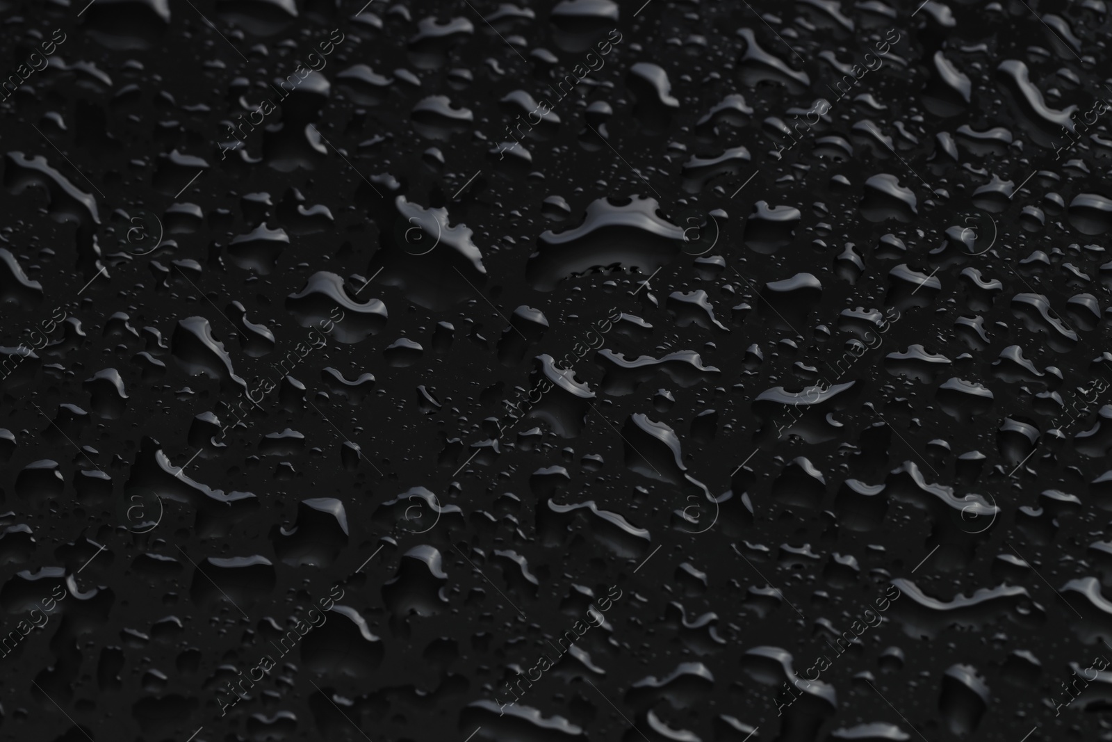 Photo of Water drops on black glass surface, closeup