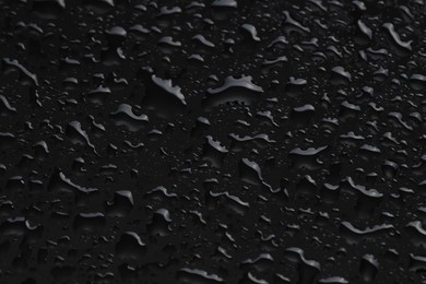 Photo of Water drops on black glass surface, closeup