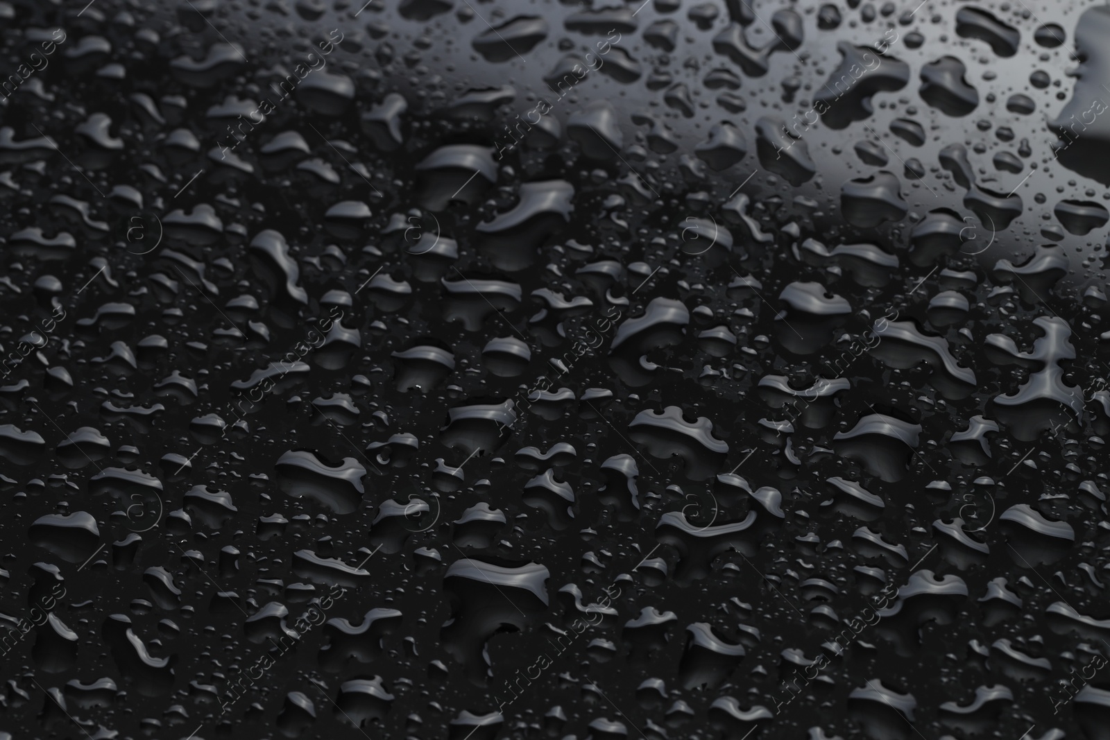 Photo of Water drops on black glass surface, closeup