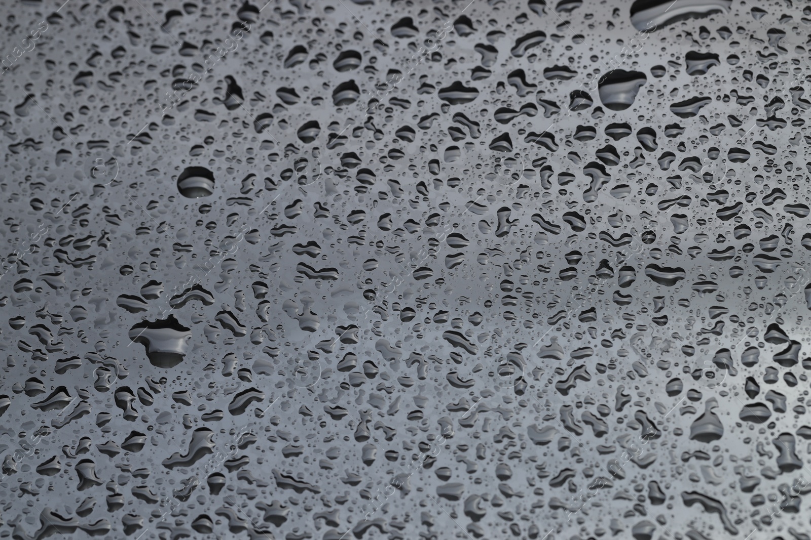 Photo of Water drops on grey glass surface, closeup