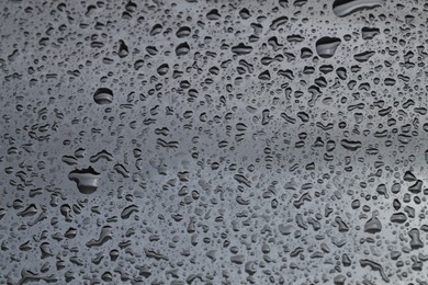 Photo of Water drops on grey glass surface, closeup