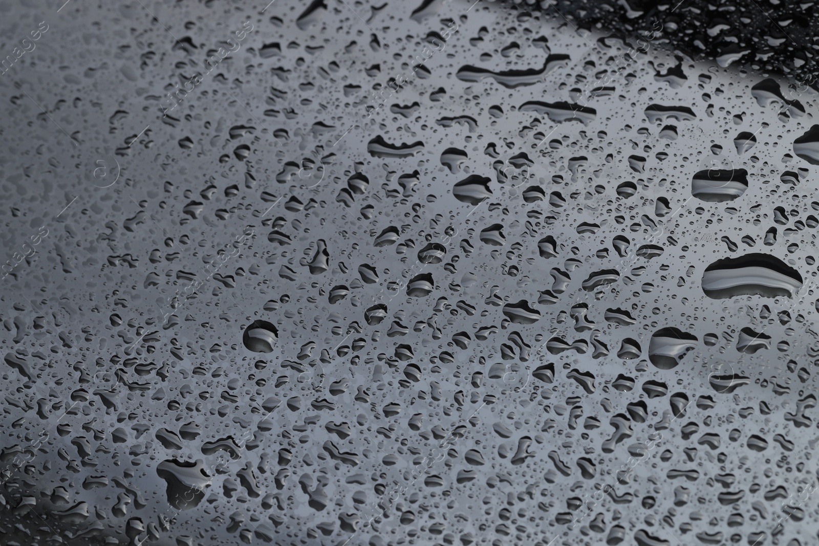 Photo of Water drops on grey glass surface, closeup