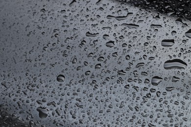 Photo of Water drops on grey glass surface, closeup