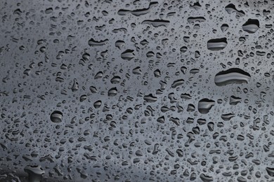 Photo of Water drops on grey glass surface, closeup