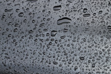 Photo of Water drops on grey glass surface, closeup