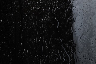 Photo of Water drops on black glass surface, closeup