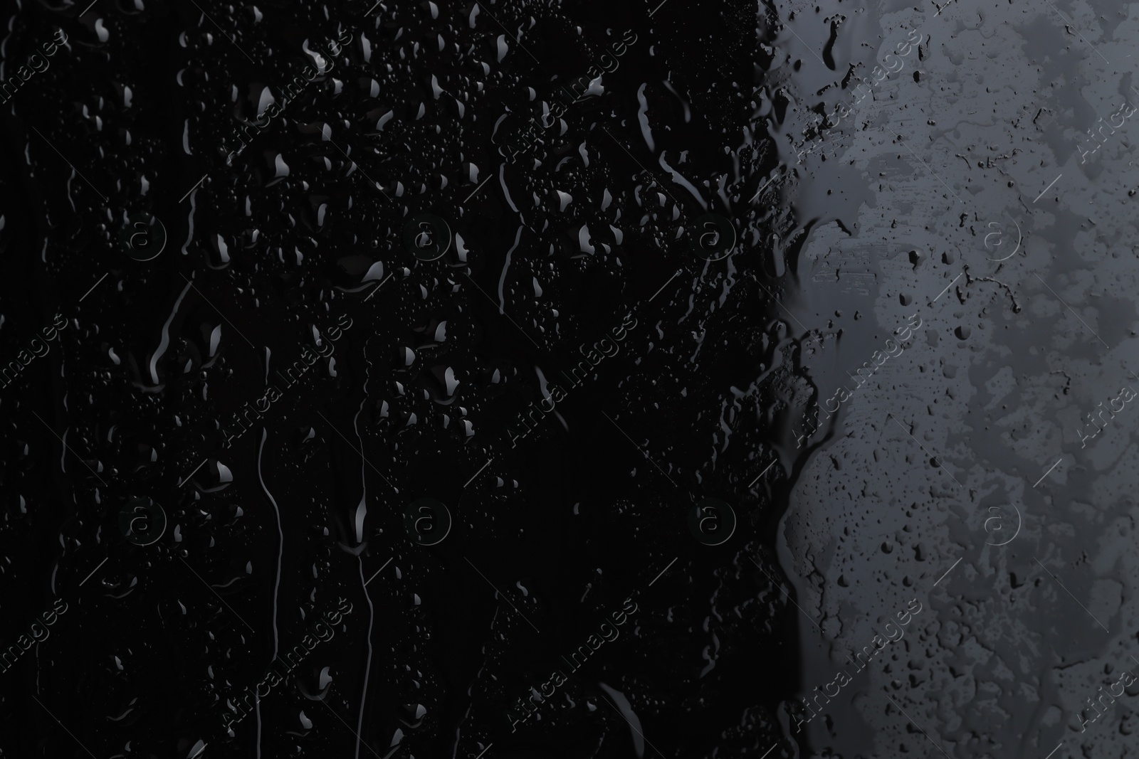 Photo of Water drops on black glass surface, closeup