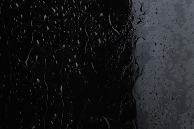 Photo of Water drops on black glass surface, closeup