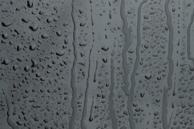 Water drops on grey glass surface, closeup