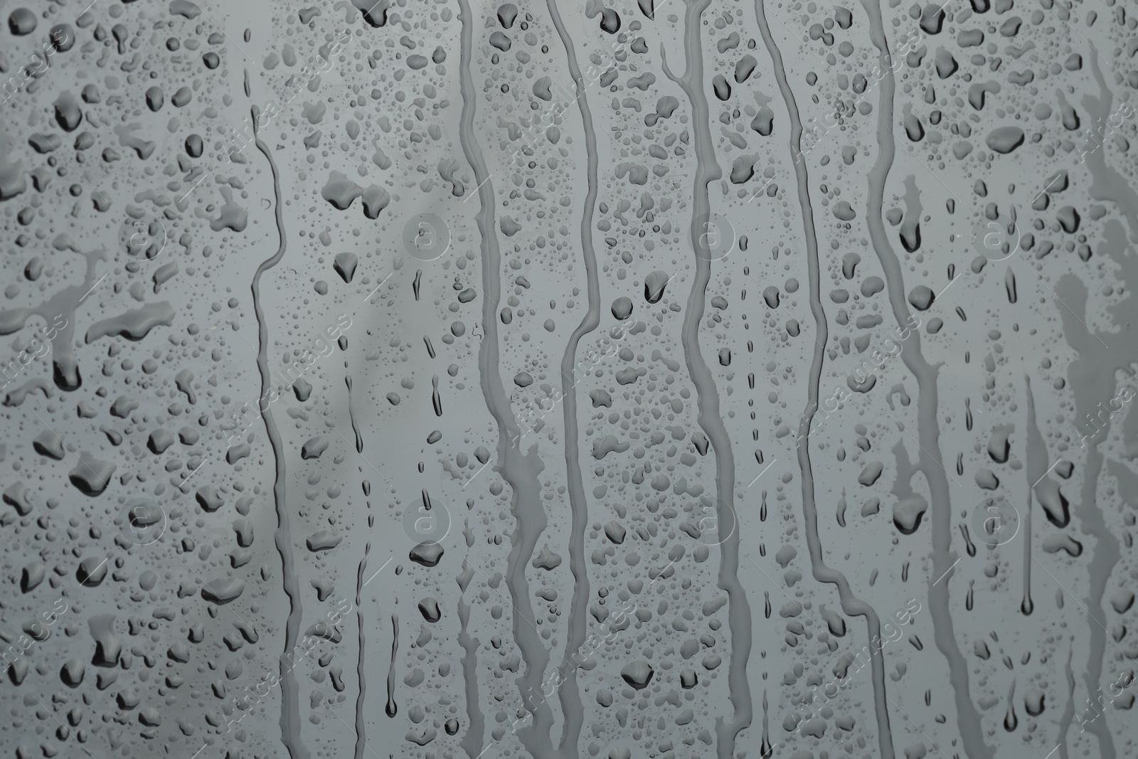 Photo of Water drops on grey glass surface, closeup