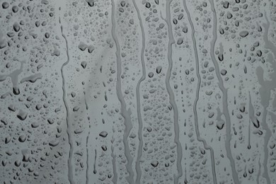 Photo of Water drops on grey glass surface, closeup