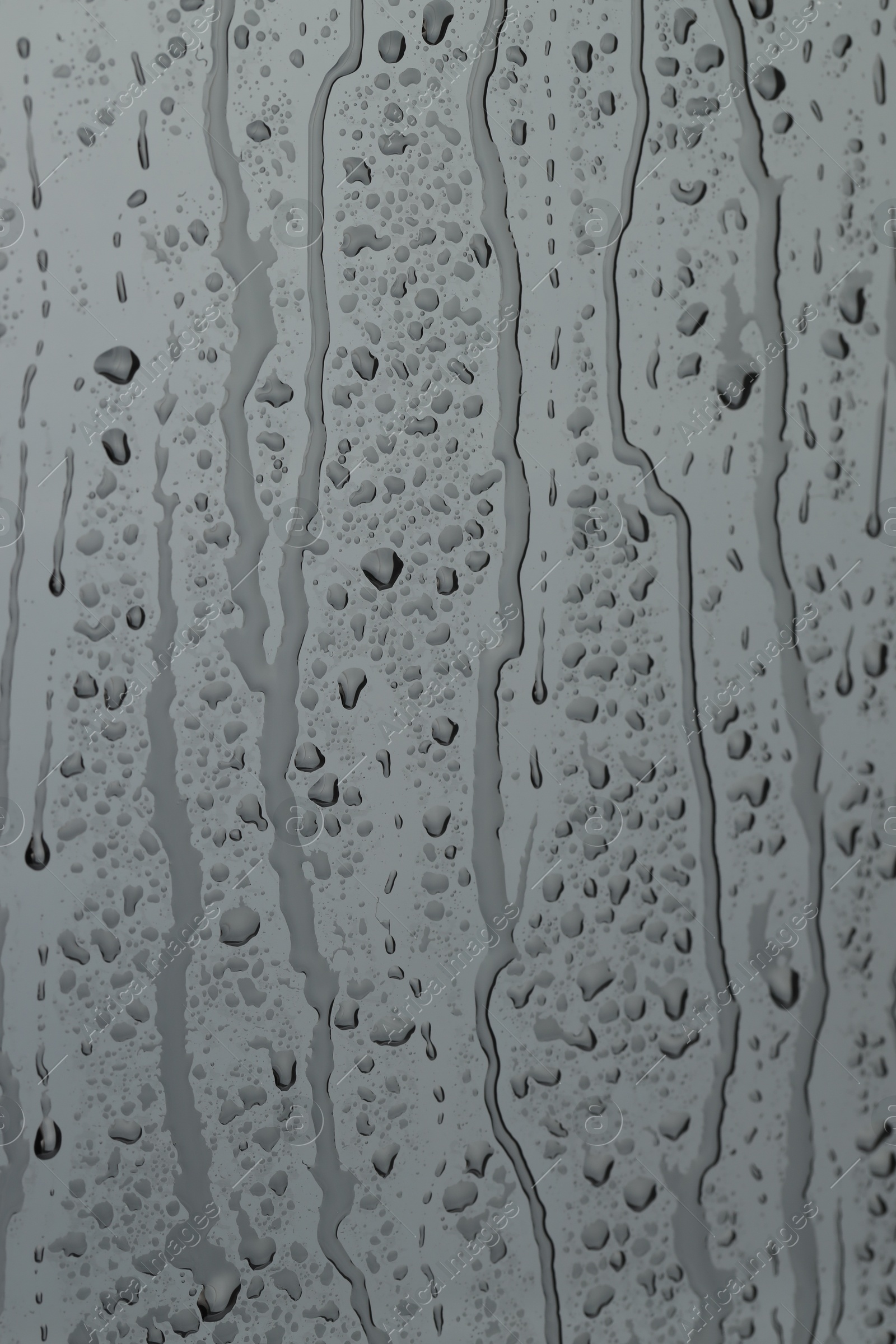 Photo of Water drops on grey glass surface, closeup