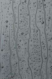 Water drops on grey glass surface, closeup