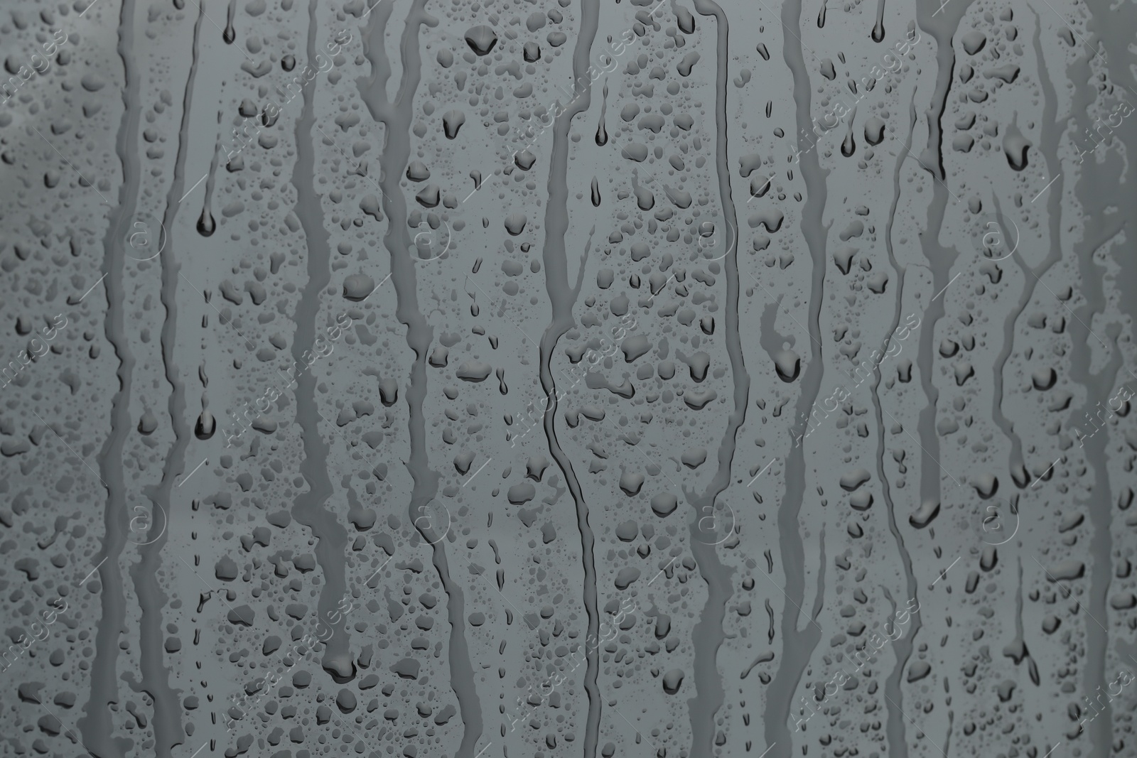 Photo of Water drops on grey glass surface, closeup