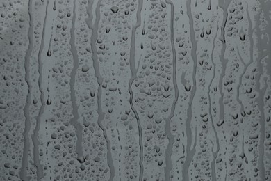 Photo of Water drops on grey glass surface, closeup