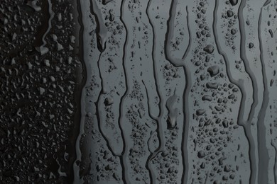 Photo of Water drops on grey glass surface, closeup