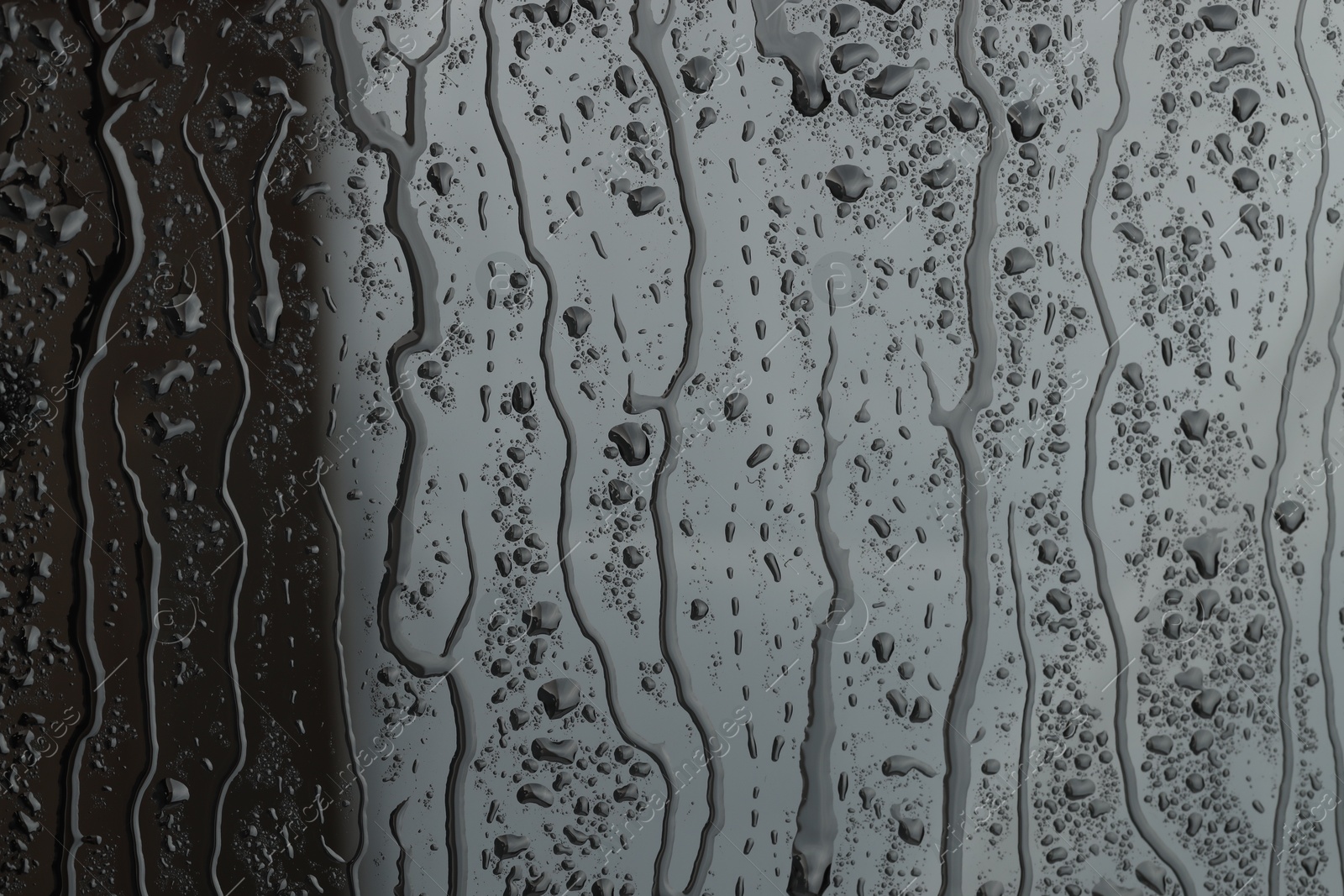 Photo of Water drops on grey glass surface, closeup