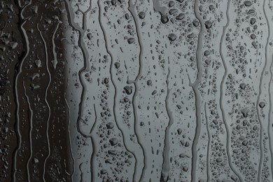 Photo of Water drops on grey glass surface, closeup