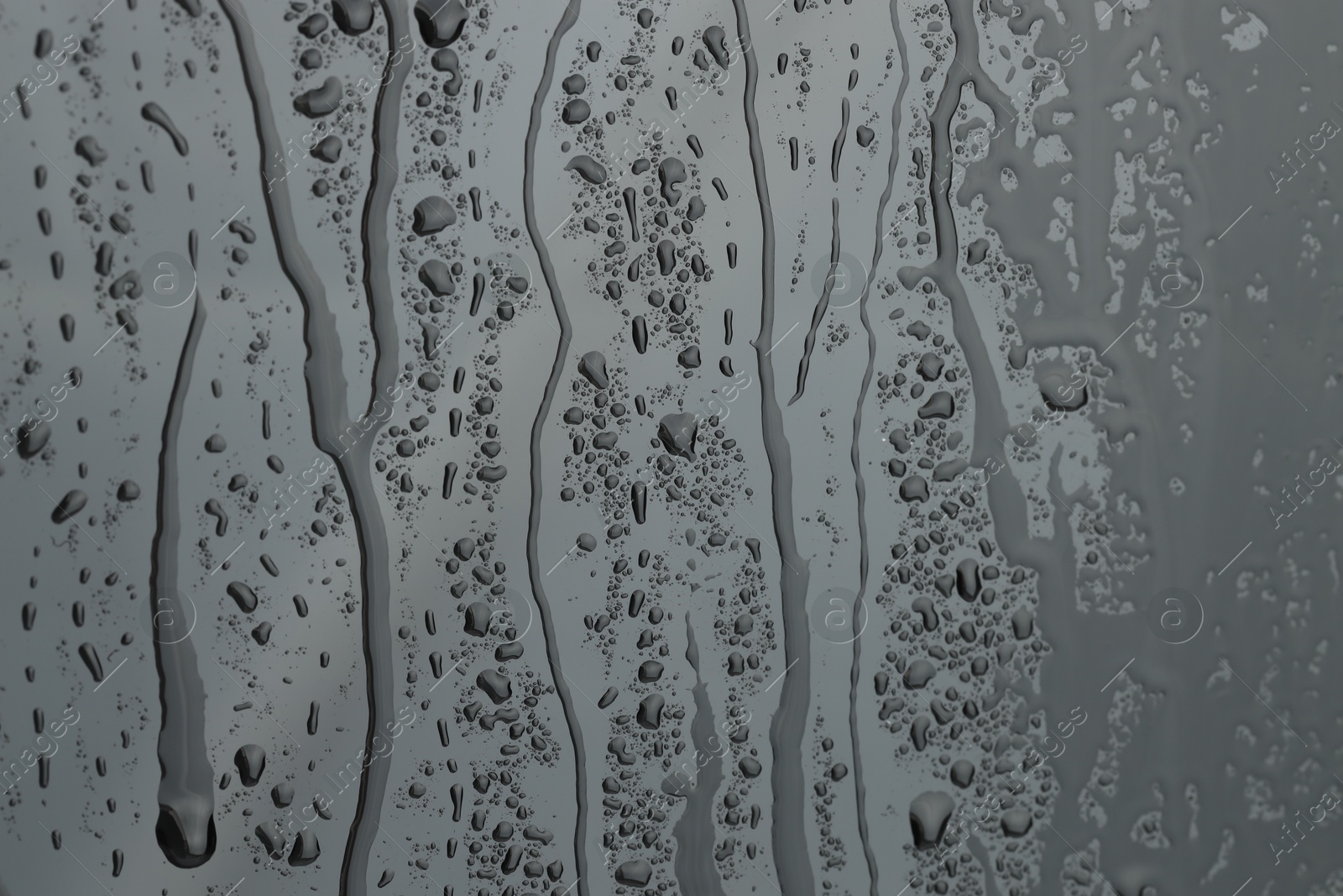 Photo of Water drops on grey glass surface, closeup