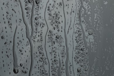 Photo of Water drops on grey glass surface, closeup