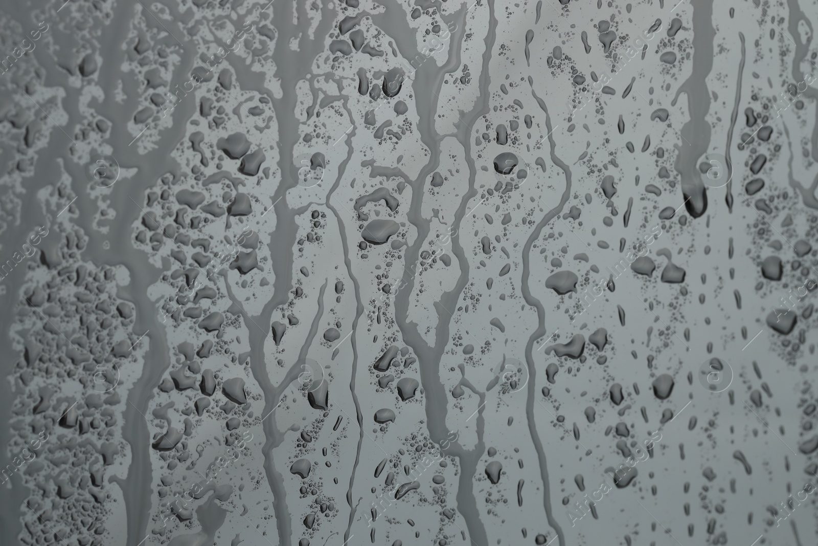 Photo of Water drops on grey glass surface, closeup