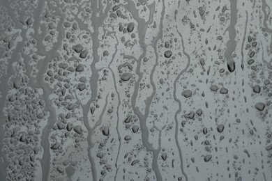 Water drops on grey glass surface, closeup