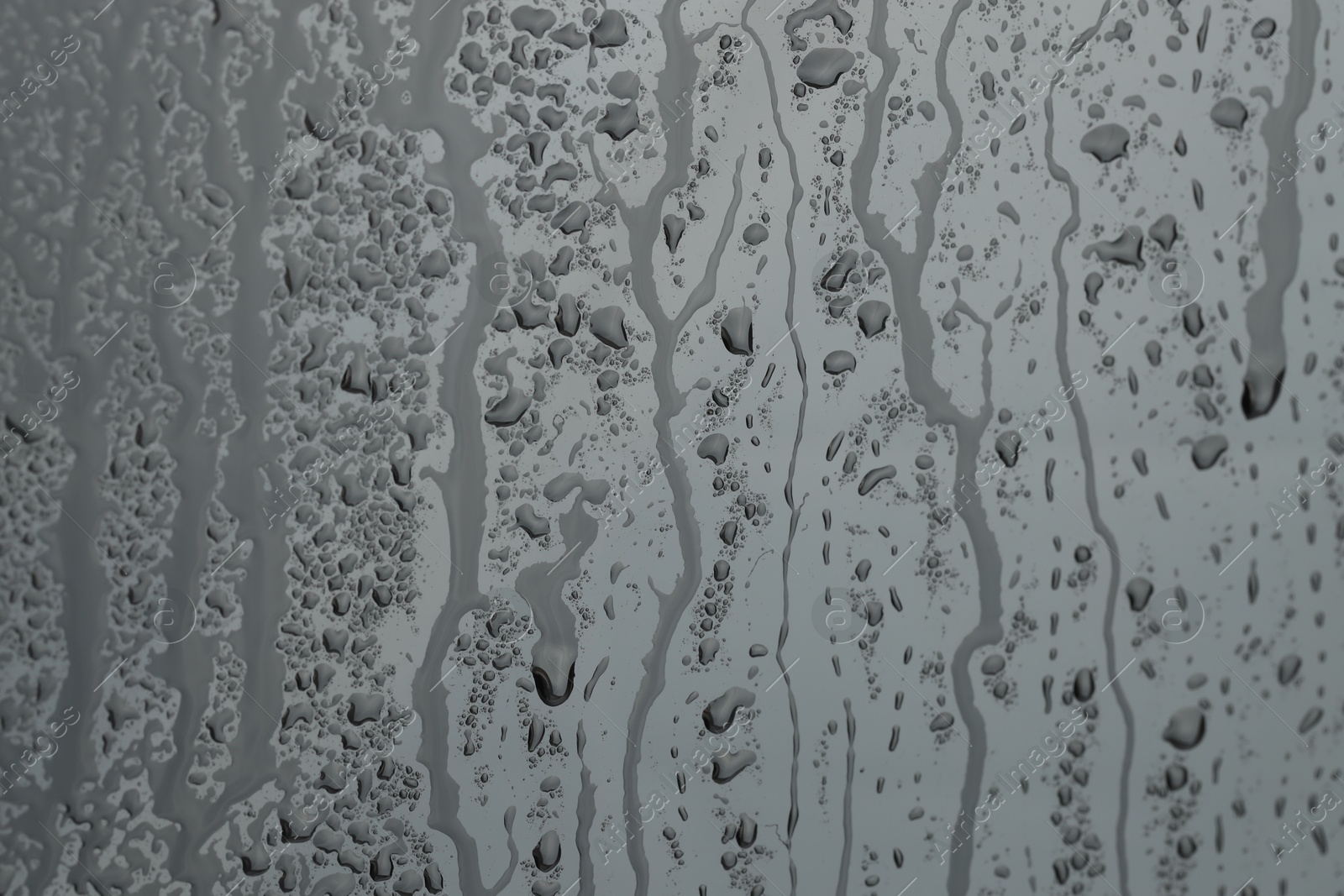 Photo of Water drops on grey glass surface, closeup