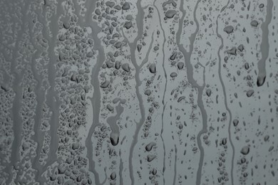 Photo of Water drops on grey glass surface, closeup