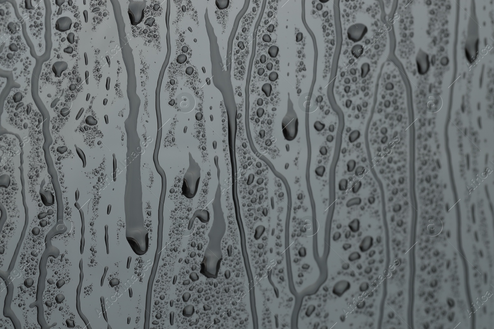 Photo of Water drops on grey glass surface, closeup