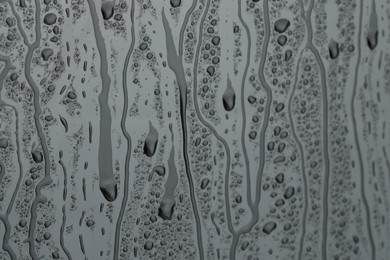 Photo of Water drops on grey glass surface, closeup