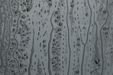 Photo of Water drops on grey glass surface, closeup