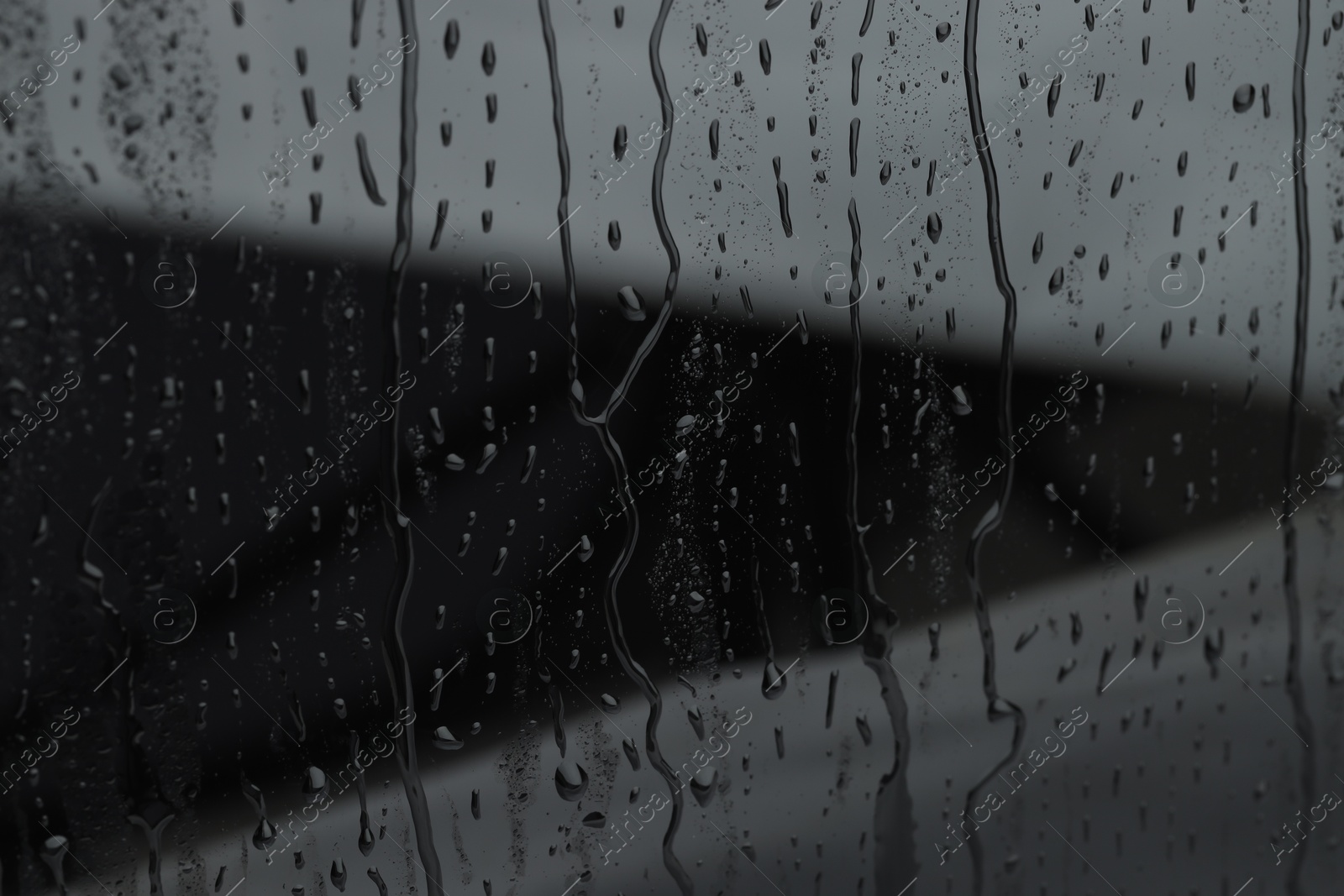 Photo of Water drops on grey glass surface, closeup