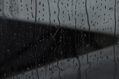 Photo of Water drops on grey glass surface, closeup