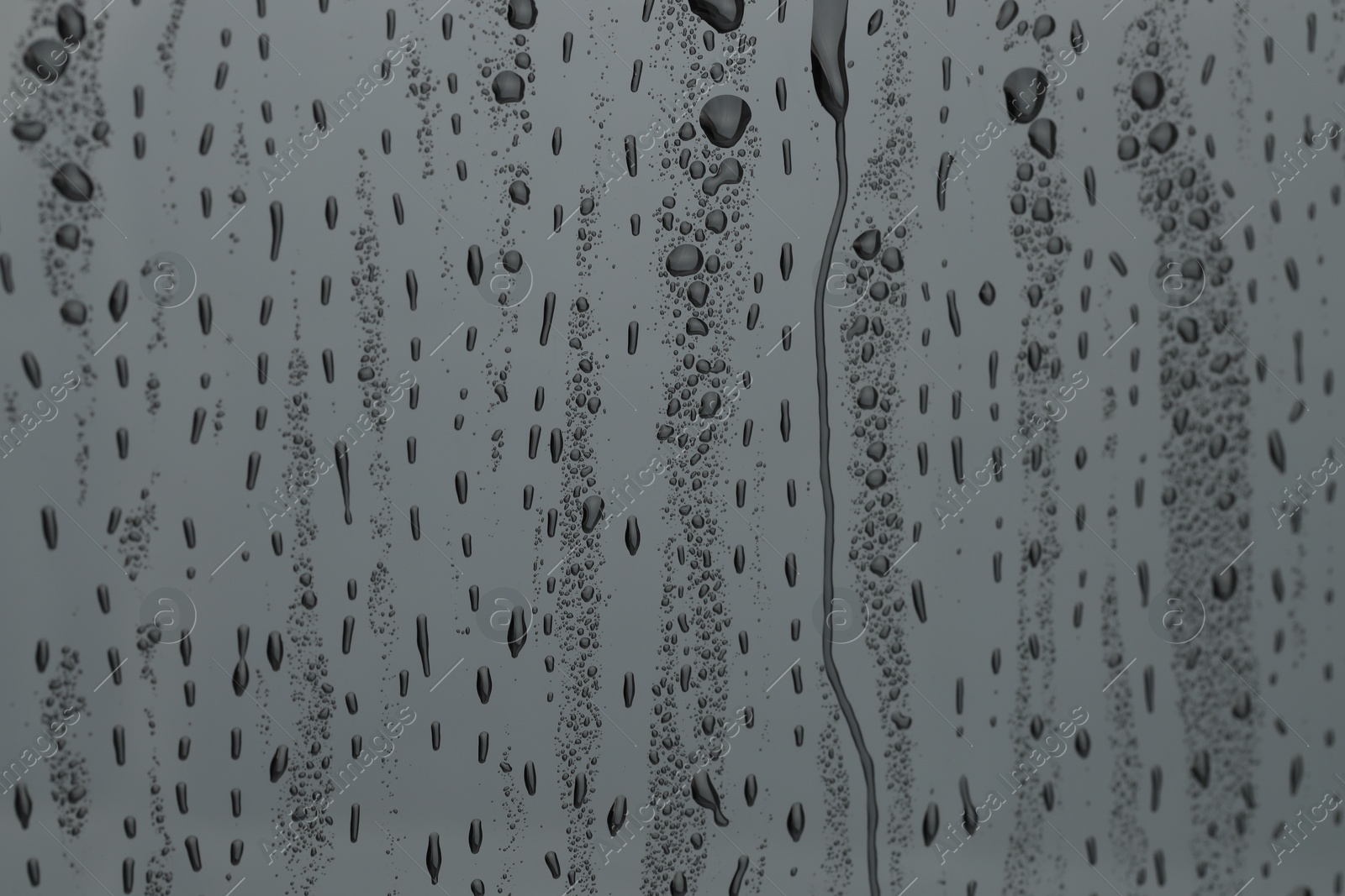 Photo of Water drops on grey glass surface, closeup