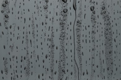 Photo of Water drops on grey glass surface, closeup