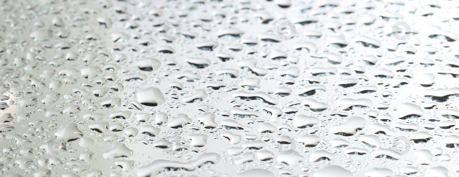 Photo of Water drops on light grey glass surface, closeup