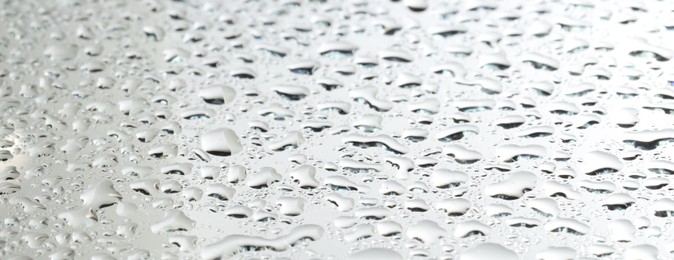 Photo of Water drops on light grey glass surface, closeup