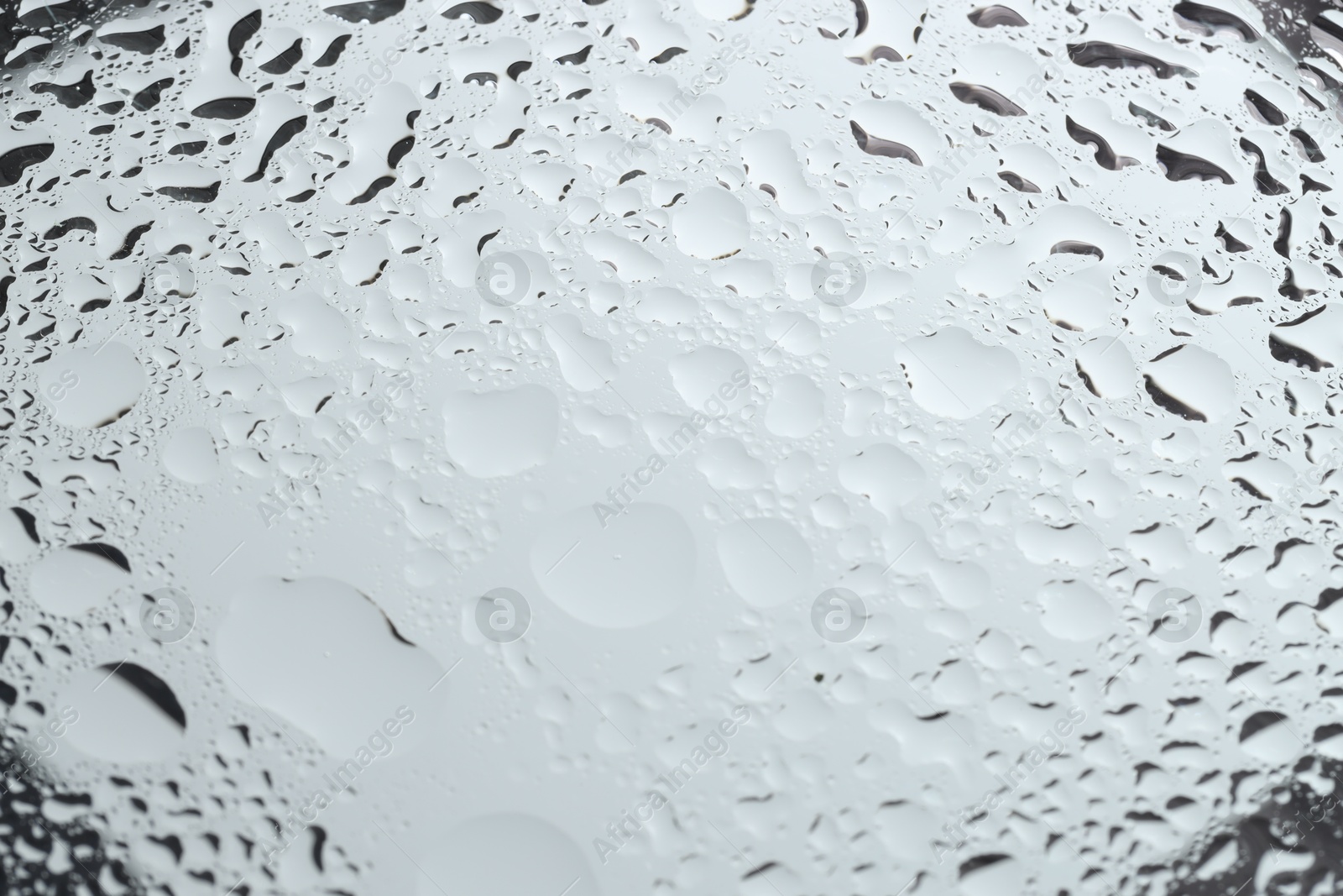 Photo of Water drops on light grey glass surface, closeup