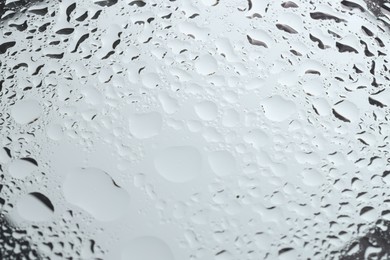 Water drops on light grey glass surface, closeup