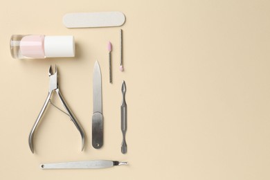 Photo of Set of pedicure tools on beige background, flat lay. Space for text