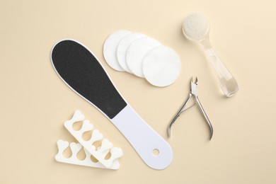 Photo of Set of pedicure tools on beige background, flat lay