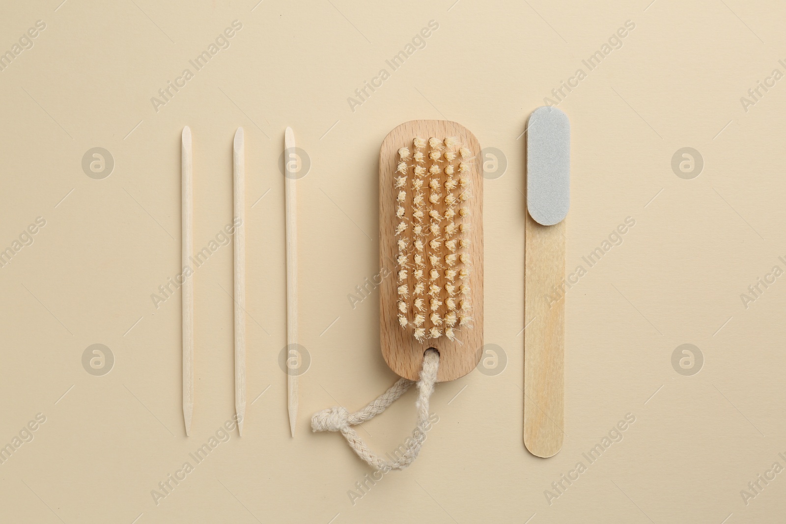 Photo of Set of pedicure tools and flowers on beige background, flat lay